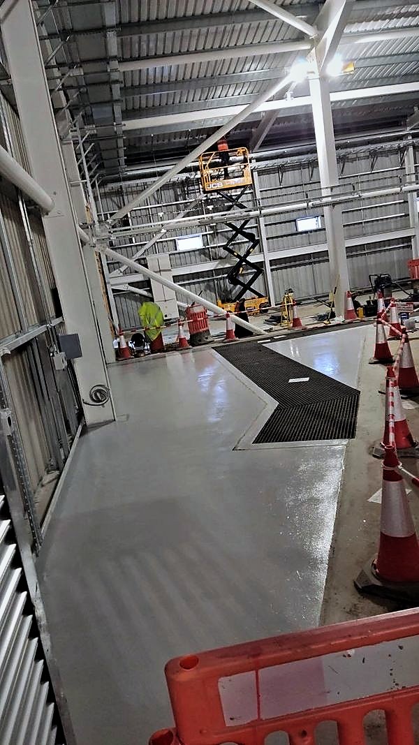 New floor coating laid around a grated drainage channel in a steel portal frame hall