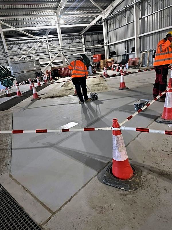 PKBC operatives applying floor coating within a coned-off area of an industrial hall