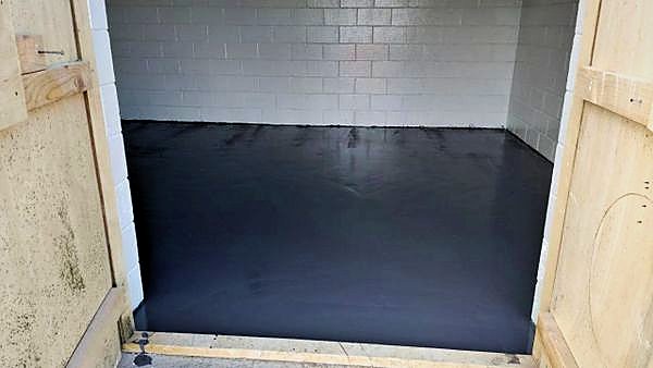 Dark grey chemical resistant floor finish in a room with coated blockwork walls