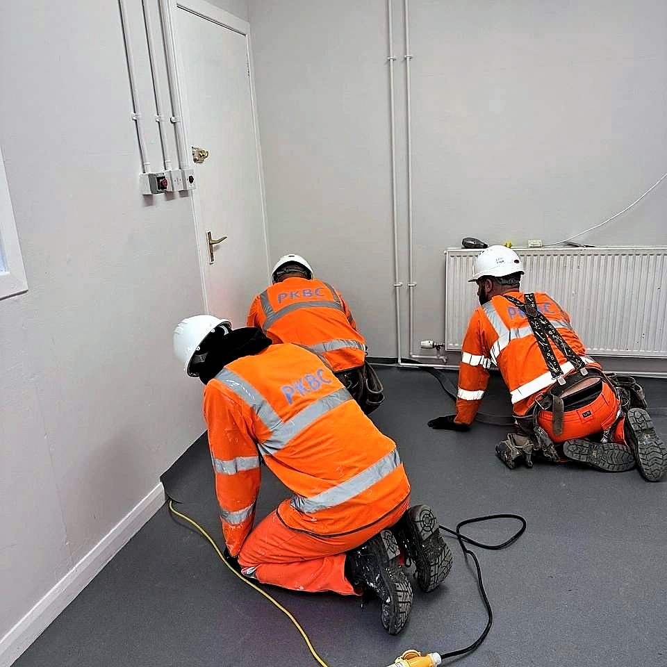 Three PKBC operatives laying flooring in a refurbished office room